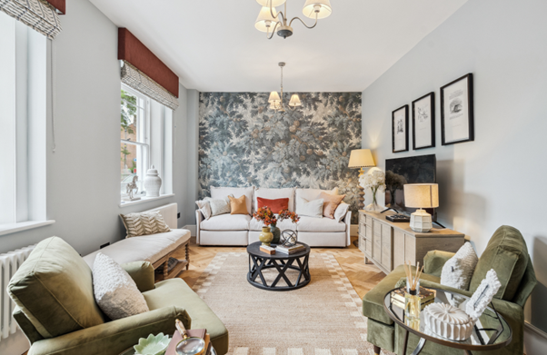Stylish living room with two green armchairs, a white sofa, patterned wallpaper, and a mix of modern and classic decor.