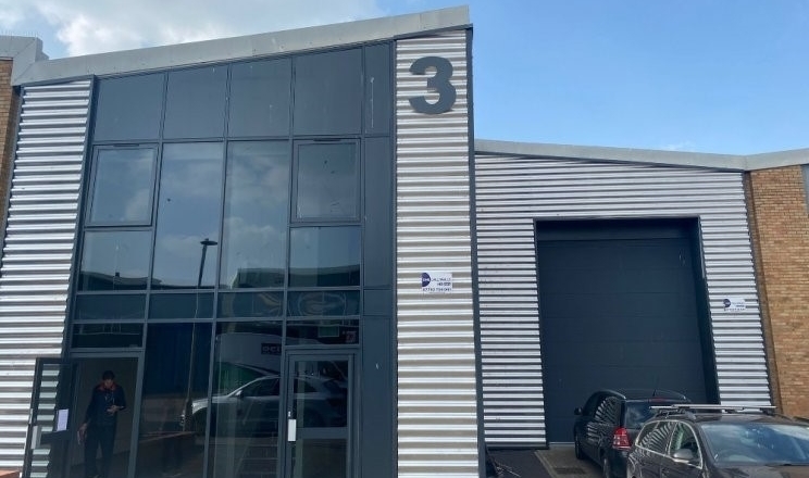 Exterior of an industrial building with a large glass entrance and a loading bay, labeled with the number 3.