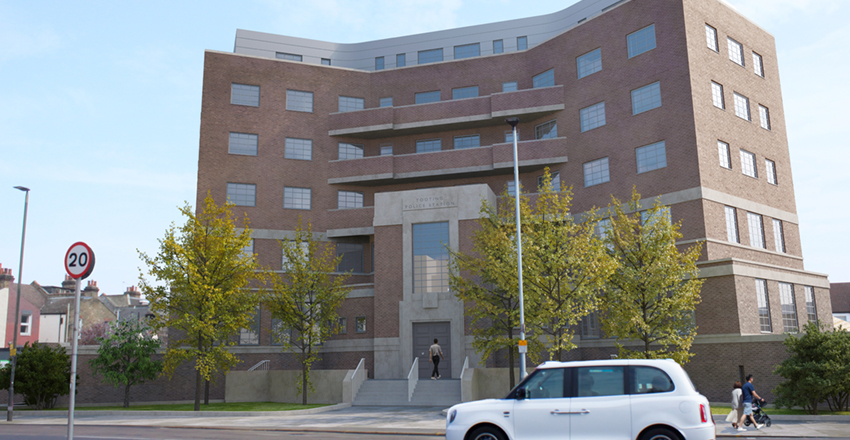 Street view of a large, modern brick building with balconies and a central entrance, with a white taxi passing by in the foreground